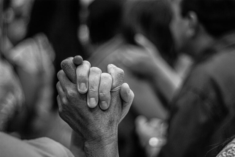 Close-up of hands clasped together in solidarity at a community gathering.
