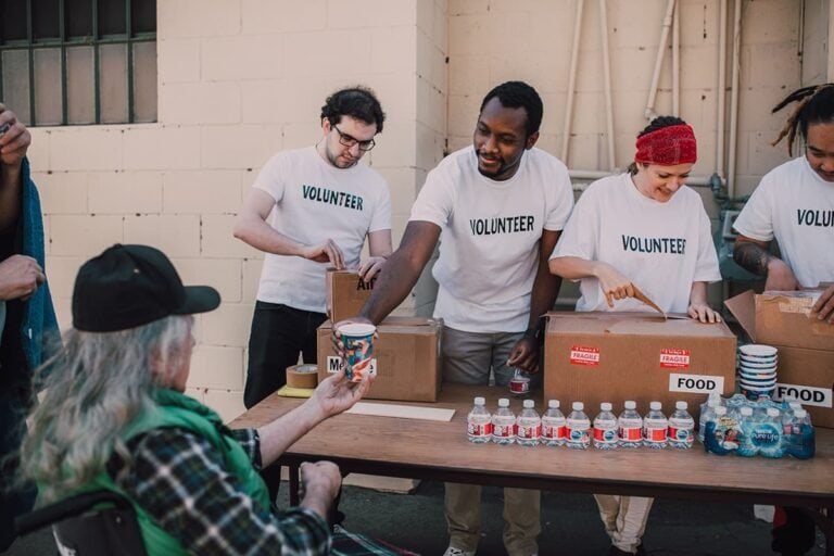 Volunteers distributing food and water to elderly at community service event.